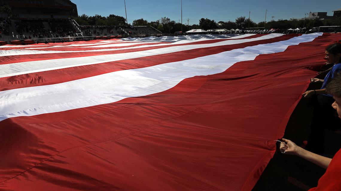 当地后备军官训练队和JROTC部队手持的战场大小的美国国旗的地面拍摄 